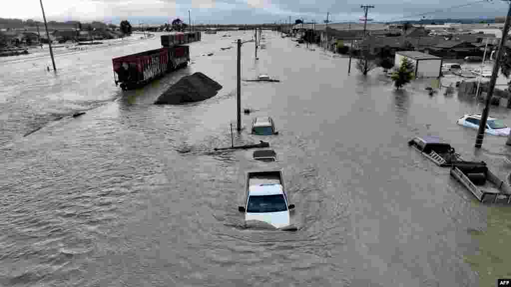 Train cars, vehicles and homes are seen in floodwaters in Pajaro, California, March 11, 2023.&nbsp;Residents were forced to evacuate in the middle of the night after an atmospheric river surge broke the the Pajaro Levee and sent flood waters flowing into the community.