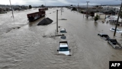 Foto udara menunjukkan gerbong kereta, kendaraan, dan rumah yang terendam banjir di kota Pajaro, California, 11 Maret 2023.