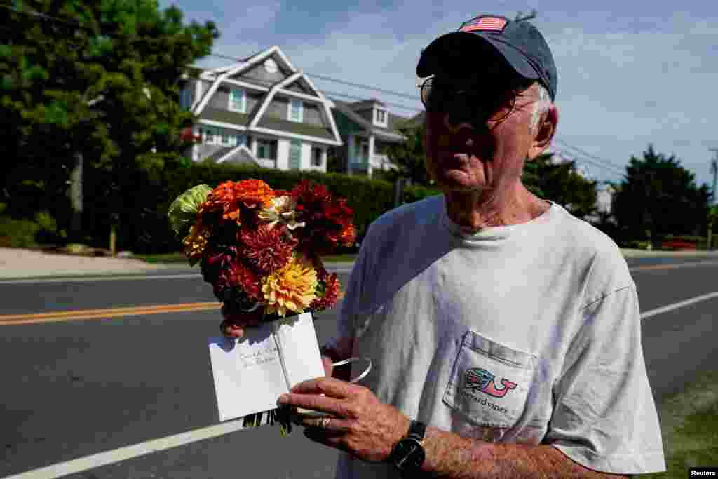 Mark Siegel, un vecino del presidente Joe Biden, sostiene flores y una nota para él y la primera dama Jill Biden, después de que anunciara que detiene su candidatura a la reelección, en Rehoboth Beach, Delaware, EEUU.