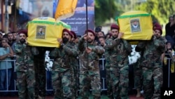 Pejuang Hizbullah membawa peti jenazah dua rekan mereka yang tewas pada hari Sabtu oleh serangan udara Israel di Lebanon selatan, selama prosesi pemakaman di pinggiran selatan Beirut, Lebanon, Minggu 28 Juli 2024.