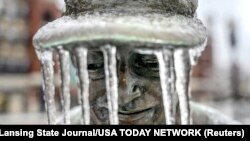 Icicles hang from the hat of a figure that is part of the Hometown Hero baseball sculpture outside Jackson Field in Lansing, Michigan.