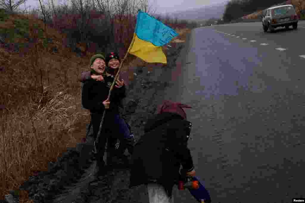 5 de enero de 2023: Al lado de una carretera en Bakhmut, niños juegan y sonríen portando una bandera de Ucrania, mientras continúan la contraofensiva por el país.