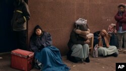 Migrants queue in the cold as they look for a shelter outside a migrant assistance center at St. Brigid Elementary School on Dec. 5, 2023, in New York.