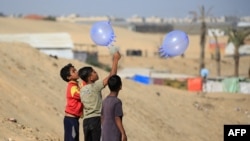 Displaced Palestinian children play with surgical rubber gloves in Rafah in the southern Gaza Strip, on May 31, 2024, amid the conflict between Israel and Hamas.