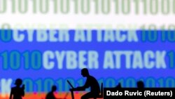 Foto ilustrasi yang menunjukkan sejumlah figur dengan komputer dan laptop di depan kata "Cyber Attack (Serangan Siber)" dan bendera Rusia. Foto diambil pada 15 Februari 2022. (Foto: Reuters/Dado Ruvic)