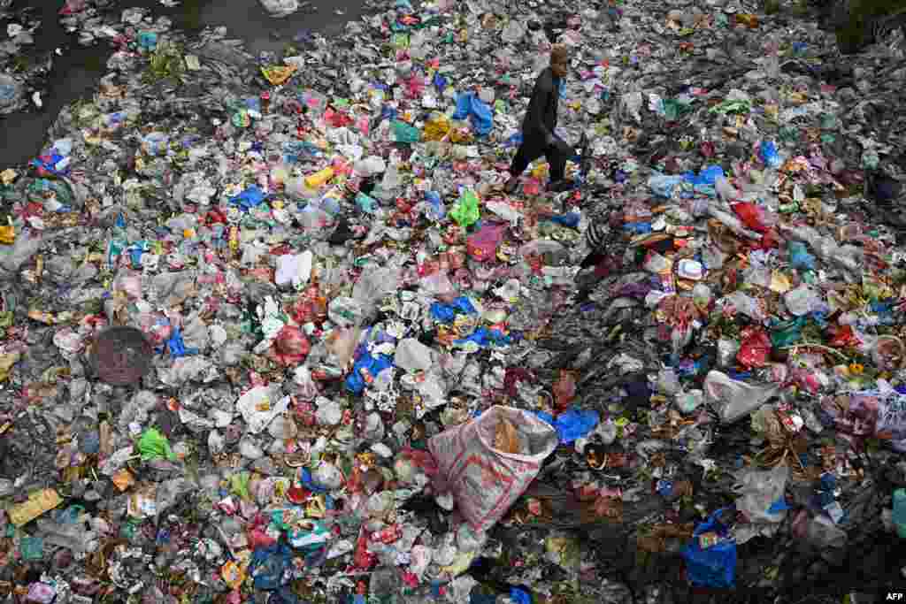 A ragpicker walks through a sewage canal filled with garbage in Rawalpindi, Pakistan.