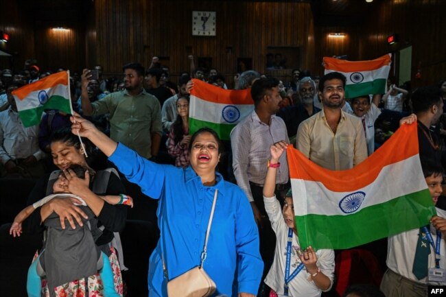 FILE - People wave India's national flag at the Nehru Science Centre in Mumbai on August 23, 2023, to celebrate the successful lunar landing of Chandrayaan-3 spacecraft on the south pole of the Moon. (Photo by Punit PARANJPE / AFP)