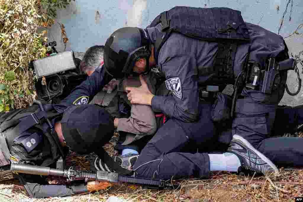 Israeli police and security forces assist a journalist taking cover during an alert for a rocket attack in Israel&#39;s southern city of Sderot near the border with Gaza.