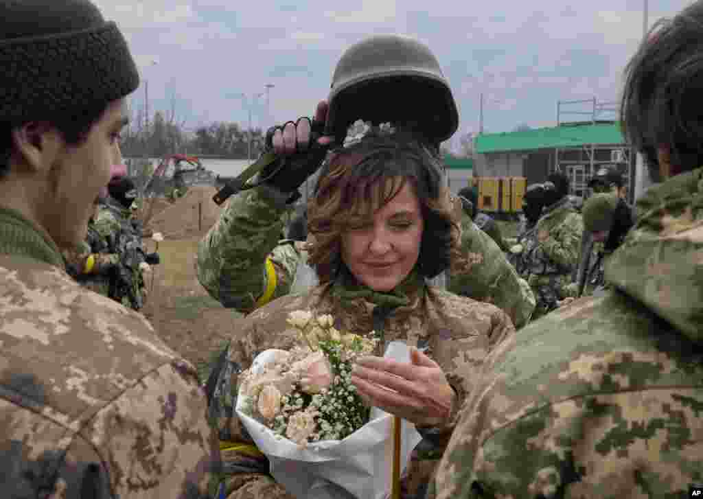 Солдат держит каску как диадему во время свадебной церемонии украинских военных на пункте пропуска в Киеве. 6 марта 2022 (AP Photo/Efrem Lukatsky)
