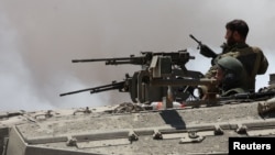 Israeli soldiers sit in a tank near the Israel-Gaza border, May 16, 2024. 