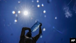 FILE - A man pours cold water onto his head to cool off on a hot day in the Mediterranean Sea in Beirut, Lebanon, July 16, 2023. As temperatures and humidity soar outside, what's happening inside the human body can become a life-or-death battle.