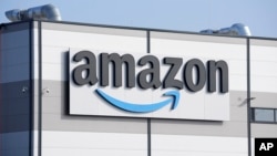FILE - An Amazon company logo is seen on the facade of a company's building in Schoenefeld near Berlin, Germany, March 18, 2022. Amazon is one of more than 40 corporations that have pledged to hire and train refugees.