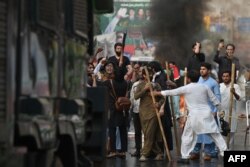 Supporters of former Prime Minister Imran Khan carrying sticks gather outside Khan's house to prevent officers from arresting him, in Lahore on March 14, 2023. (Photo: AFP/Arif Ali)