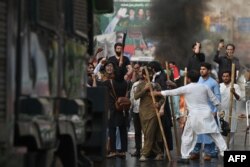 Pendukung mantan Perdana Menteri Imran Khan membawa tongkat berkumpul di luar rumah Khan untuk mencegah petugas menangkapnya, di Lahore pada 14 Maret 2023. (Foto: AFP/Arif Ali)