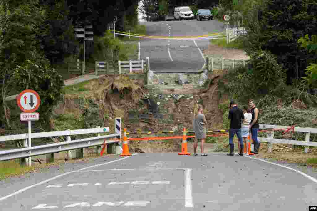Residents stand next to the Puketapu bridge washed away during Cyclone Gabrielle near Napier, New Zealand.