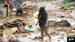A resident walks amongst debris of destroyed belongings next to her house at a village in Manila on July 25, 2024, a day after heavy rains fueled by Typhoon Gaemi and the seasonal monsoon lashed Manila and surrounding regions.