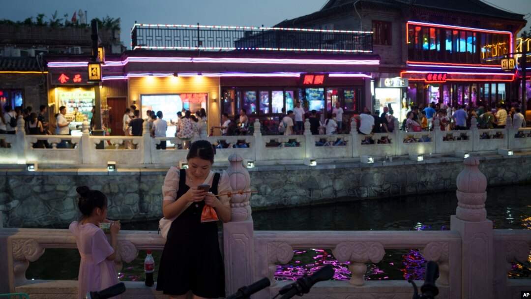 Žena gleda u svoj telefon u pabu na jezeru Shichahai u Pekingu, 16. jula 2024.