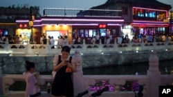 A woman looks at her phone at Shichahai lake pub area in Beijing, July 16, 2024.