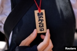 Rickshaw puller Yuka Akimoto, 21, shows her wooden tag reading "I don't want to give up" during her guided tour around Asakusa district in Tokyo July 11, 2023.