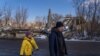 A man and a young girl walk by one of the many bridges destroyed in Kupiansk, Feb. 17, 2023.