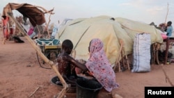 FILE - Fayrouz, 10, a Sudanese girl who fled the conflict in Geneina in Sudan's Darfur region, gives a bath to her brother Awad, 6, outside their makeshift shelter in Adre, Chad, Aug. 5, 2023. 