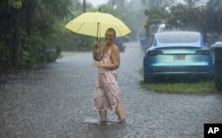 Laura Collinhofer sostiene un paraguas después de trasladar su auto a un terreno más alto mientras caen fuertes lluvias en partes del sur de Florida el miércoles 12 de junio de 2024, en Hollywood, Florida. (Matias J. Ocner/Miami Herald vía AP)