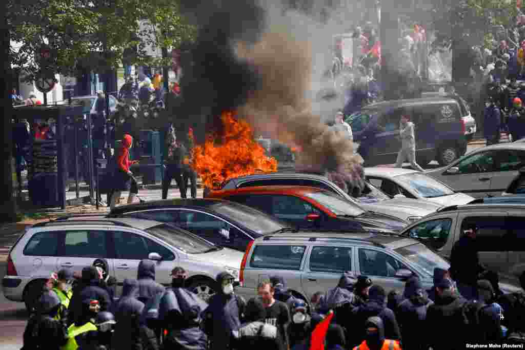 Manifestantes caminham perto de um carro em chamas durante a tradicional marcha do Dia do Trabalhador, em protesto contra a lei francesa de reforma e por justiça social, em Nantes, França, 1º de maio de 2023