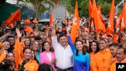 A candidata presidencial da oposição Maria Corina Machado, ao centro à direita, e o líder da oposição Freddy Superlano, ao centro à esquerda, levantam os braços para os fotógrafos durante um evento de campanha em Caracas, Venezuela, a 13 de outubro de 2023. 