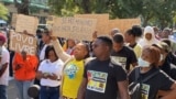 Manifestante exibe cartaz dizendo "Se há mínimo que haja salário máximo", durante marcha em Maputo pela democracia e melhores condições de vida. 24 junho 2023