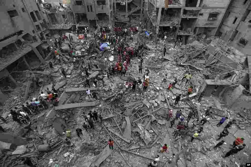 Palestinians inspect the damage of destroyed buildings following Israeli airstrikes on Gaza City.