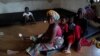 FILE - Diana Essandoh, whose husband died in an explosion when carrying mining explosives detonated along a road in Apiate, sits with her children and mother-in-law, at a shelter for displaced victims in Bogoso, Ghana, Jan. 22, 2022. 