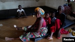 FILE - Diana Essandoh, whose husband died in an explosion when carrying mining explosives detonated along a road in Apiate, sits with her children and mother-in-law, at a shelter for displaced victims in Bogoso, Ghana, Jan. 22, 2022. 