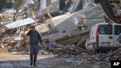 A man walks past debris from destroyed buildings in Antakya, southeastern Turkey, Feb. 21, 2023. 