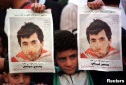 FILE - Seorang anak Palestina mengangkat poster Yahya Ayyash dalam sebuah acara peringatan untuk pembuat bom Hamas, 9 Januari 1996. Ayyash dilaporkan tewas ketika sebuah telepon seluler yang dipasangi bom meledak di tempat persembunyiannya di Gaza.