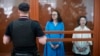 Theater director Zhenya Berkovich, right, and playwright Svetlana Petriychuk look at the media as they stand in a glass cage prior to a hearing in a court in Moscow, July 8, 2024.