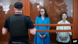 Theater director Zhenya Berkovich, right, and playwright Svetlana Petriychuk look at the media as they stand in a glass cage prior to a hearing in a court in Moscow, July 8, 2024.