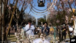 A man and a woman pray after laying flowers in front of a memorial marking the 12th anniversary of the massive earthquake, tsunami and nuclear disaster, at Hibiya Park in Tokyo, March 11, 2023.