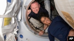 In this photo provided by NASA, Boeing Crew Flight Test astronauts Butch Wilmore, left, and Suni Williams pose inside the International Space Station's Harmony module and Boeing's Starliner spacecraft on June 13, 2024. (NASA via AP)