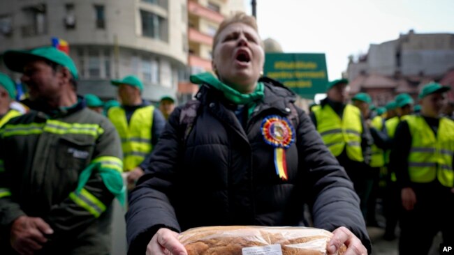 FILE - A woman holds bread during a farmers protest in Bucharest, Romania, April 7, 2023. Poland, Hungary, Slovakia and Bulgaria have banned Ukraine’s food exports to protect their own markets. They say they can't compete with Ukraine's low prices.