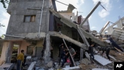 Palestinians inspect the rubble of destroyed building that the Israeli military said targeted the house of an Islamic Jihad member in Zeitoun neighborhood in Gaza City, Saturday, May 13, 2023.