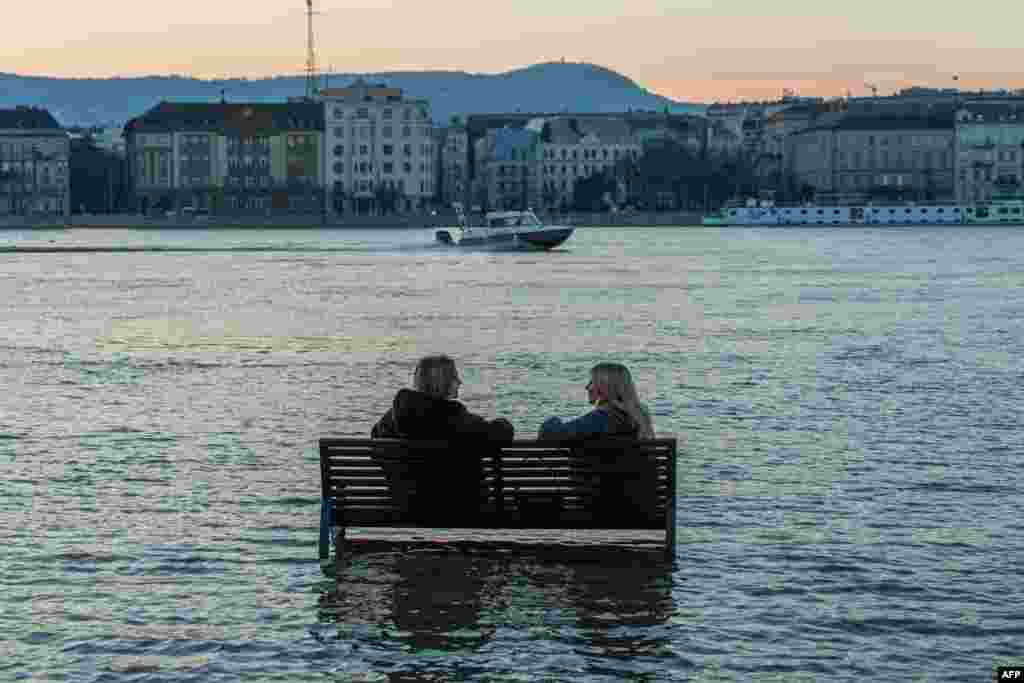 Women sit on a bench surrounded by flood water of the River Danube in Budapest, Hungary. The river burst its banks due to unusually wet and warm weather.