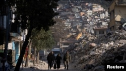 A Turkish serviceman walks with two others in the aftermath of a deadly earthquake in Antakya, Turkey, Feb. 16, 2023. Reporters have been taking and sharing images of the communities ravaged by the quake since it struck on Feb. 6, 2023.