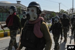 Security personnel move towards Pakistan Tehreek-e-Insaf (PTI) party activists and supporters of former Pakistan's Prime Minister Imran Khan protesting against the arrest of their leader, in Peshawar on May 10, 2023.