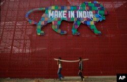 FILE - Para pekerja membawa tumpukan kayu untuk persiapan KTT Make In India di Mumbai, India, 9 Februari 2016. (AP/Rafiq Maqbool)