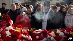 An Orthodox priest conducts a service at a makeshift memorial in front of the Crocus City Hall in the outskirts of Moscow, Russia, March 25, 2024. 