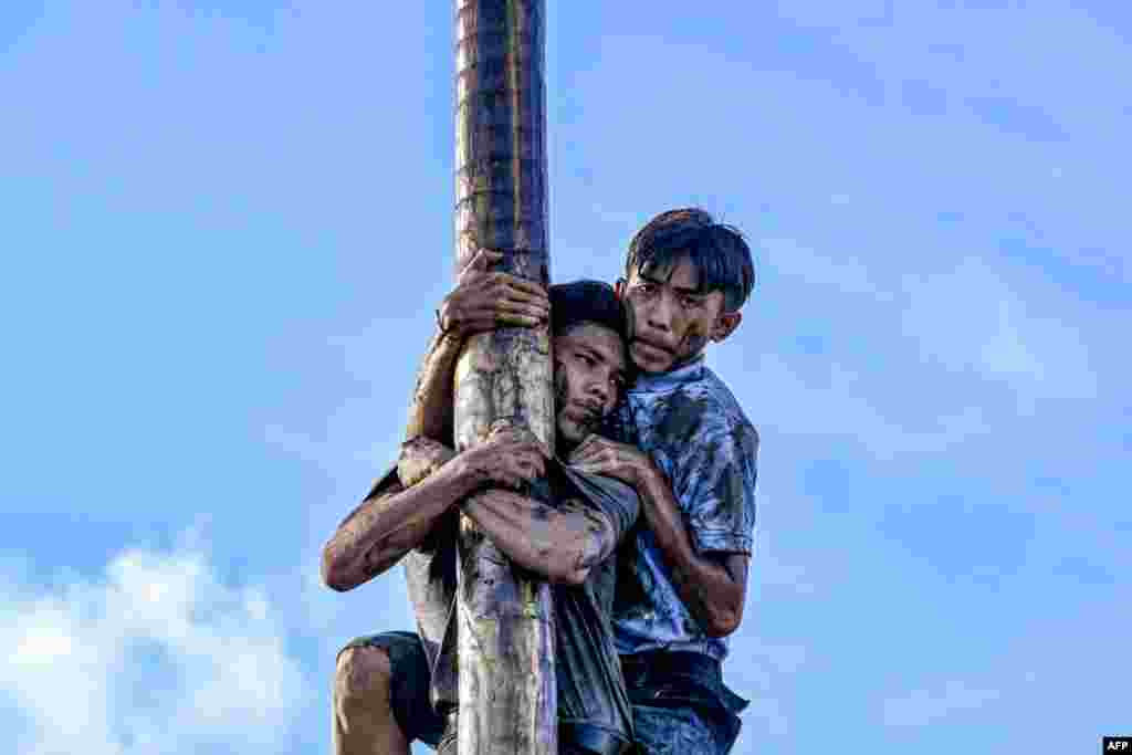Participants climb a greasy pole called "Panjat Pinang" to collect prizes hung at the top during a continuous celebration since three days of Indonesia's 78th Independence Day, in Banda Aceh, Indonesia, Aug. 20, 2023. 