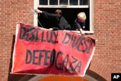 Activists hang a placard from a window of an upper floor of a building at Rhode Island School of Design, May 7, 2024, in Providence, R.I., as students and supporters are demanding that the school condemn Israel's war effort in Gaza.