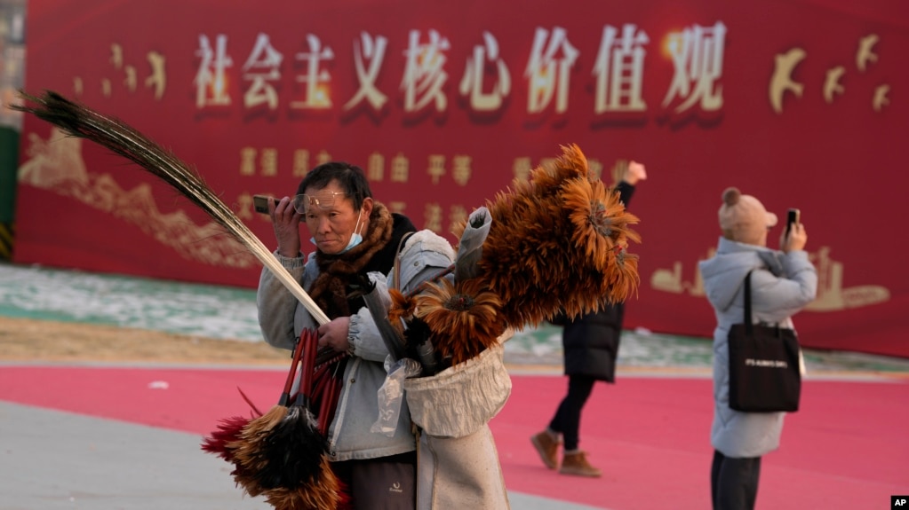 资料照：北京一名街头小贩走过“社会主义核心价值观”的宣传牌。（2024年1月20日）