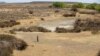 FILE - In this Sept. 24, 2021 file photo, a shepherd stands in the dry riverbed at Colesberg, Northern Cape, South Africa.