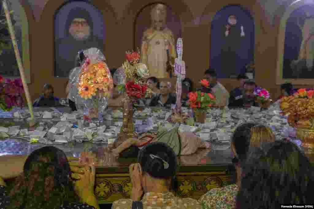 Pilgrims write wishes on small papers and toss them toward a monastery shrine Near Assiut, Egypt, Aug. 15, 2023. The Coptic ritual is a source of solace and relief, especially after repeated currency devaluations and grinding food inflation.